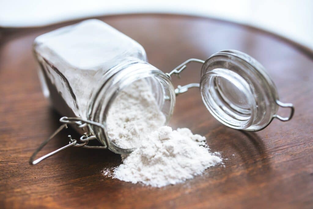 glass baking soda container slipped over a table with an open cover