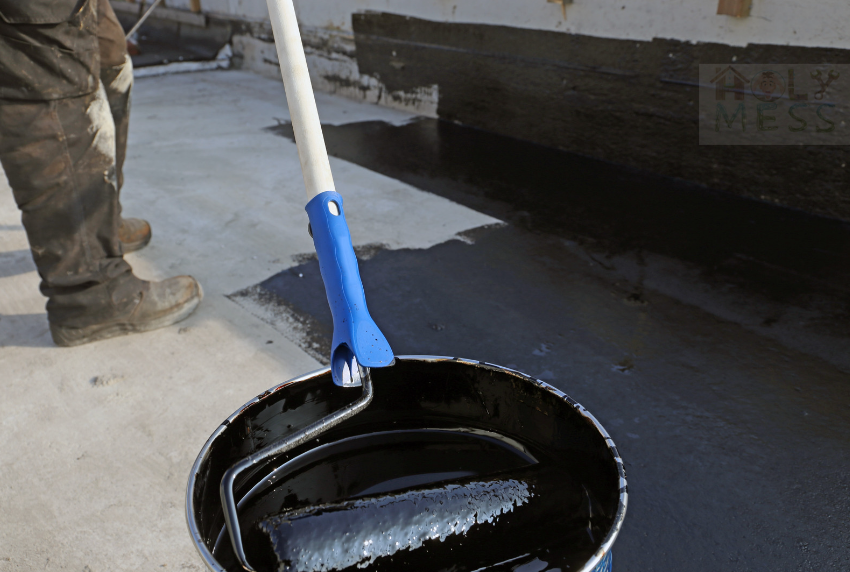 man holding paint stick dipped in a black paint bucket