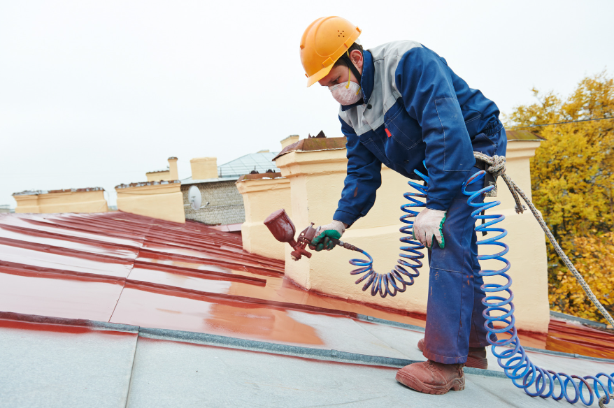 roofer working on roof holding red spray paint 
