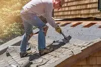 Blocked gutters and a roofer is trying to unblock them by removing waste material