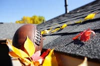 A tradesman is removing debris from the dirty roof which as part of the cleaning process