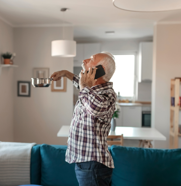 Man holding plate to collect roof leak water