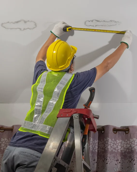  roofer on a ladder checking leak